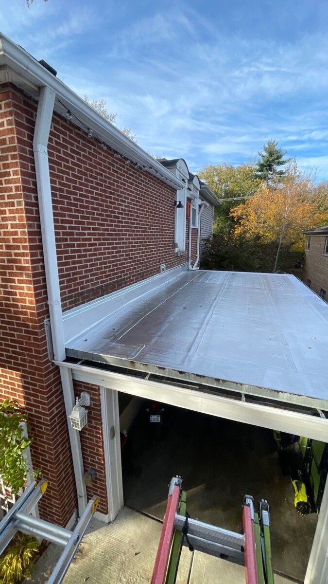 A ladder is sitting on the side of a house next to a garage door.