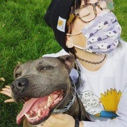 A woman wearing a face mask is holding a dog.