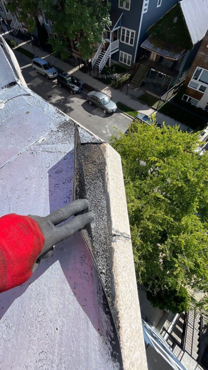 A person is holding a pair of pliers on top of a building.
