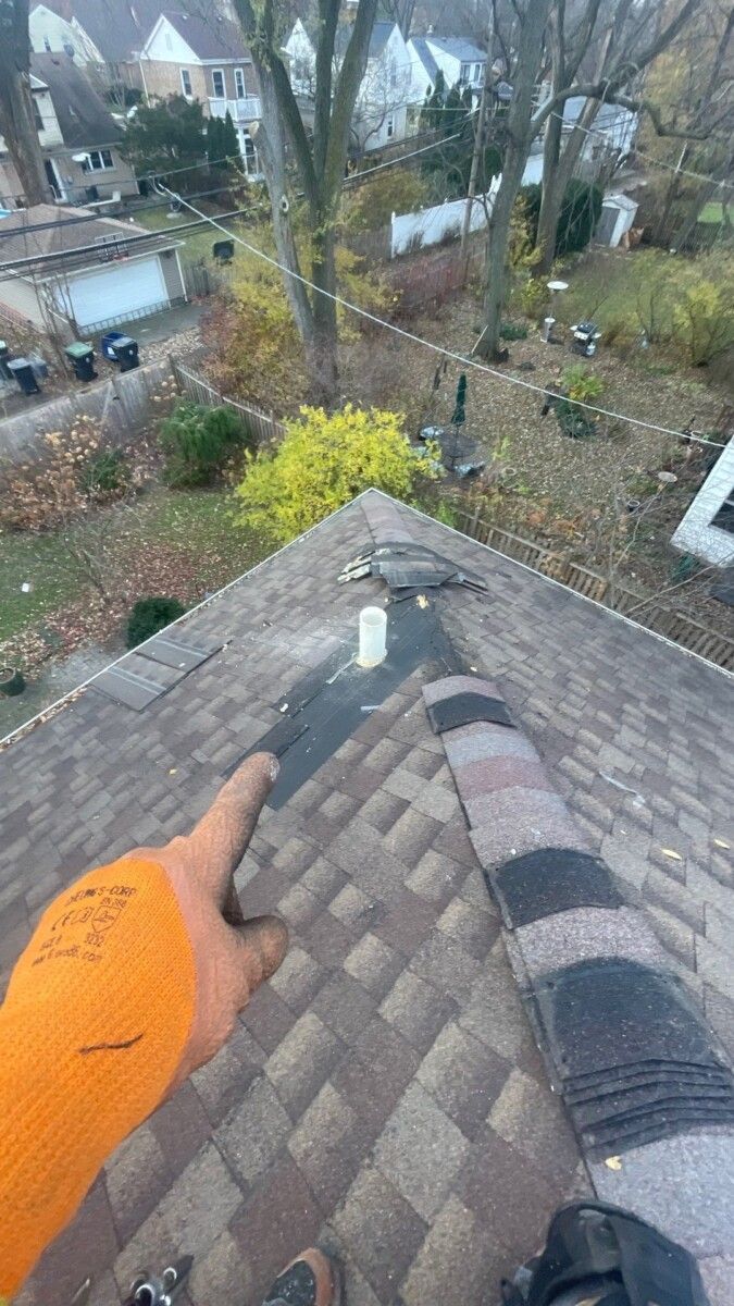A person is standing on top of a roof holding a hammer.