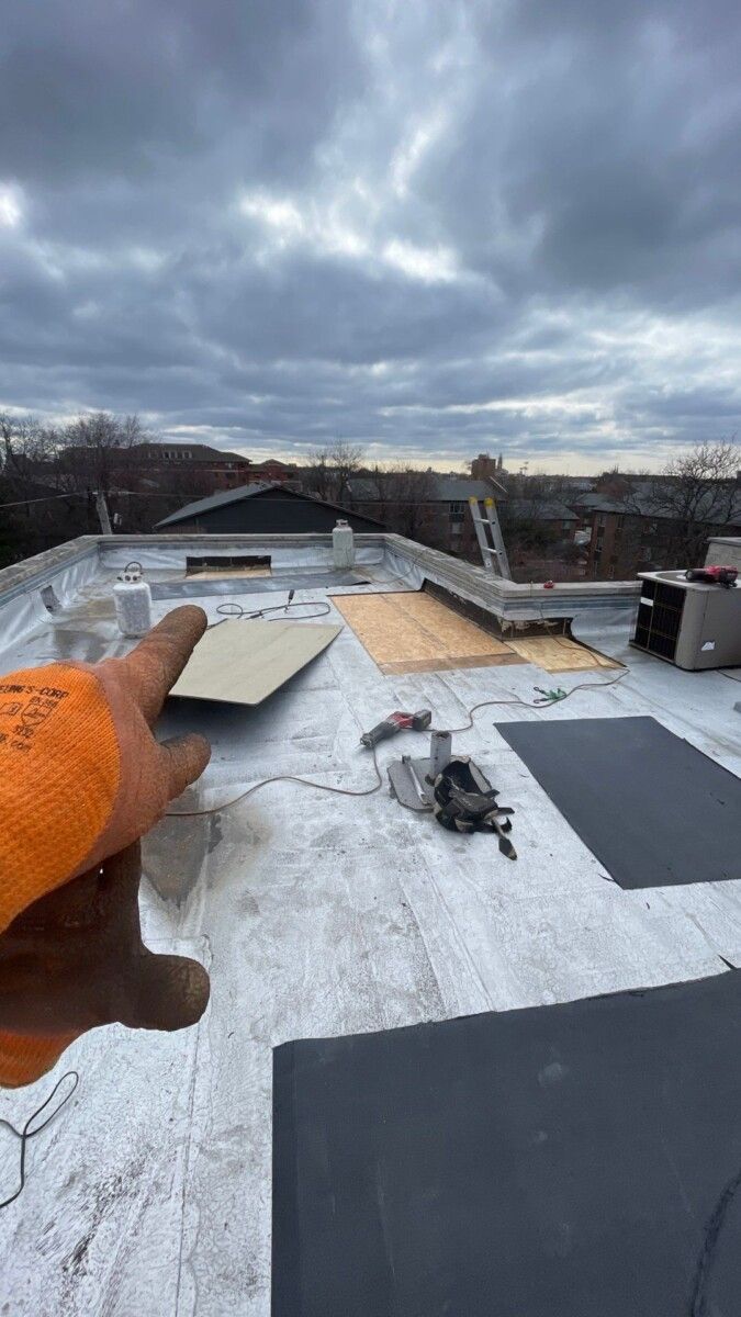 A person is holding a piece of plywood on top of a roof.