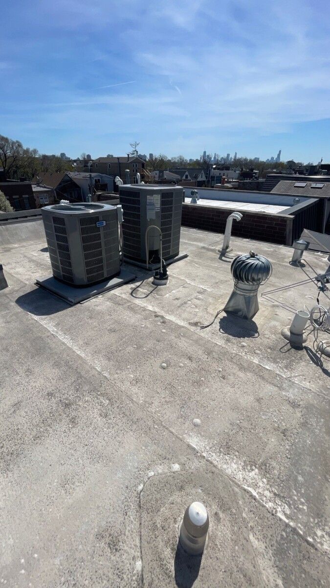 There are two air conditioners on the roof of a building.