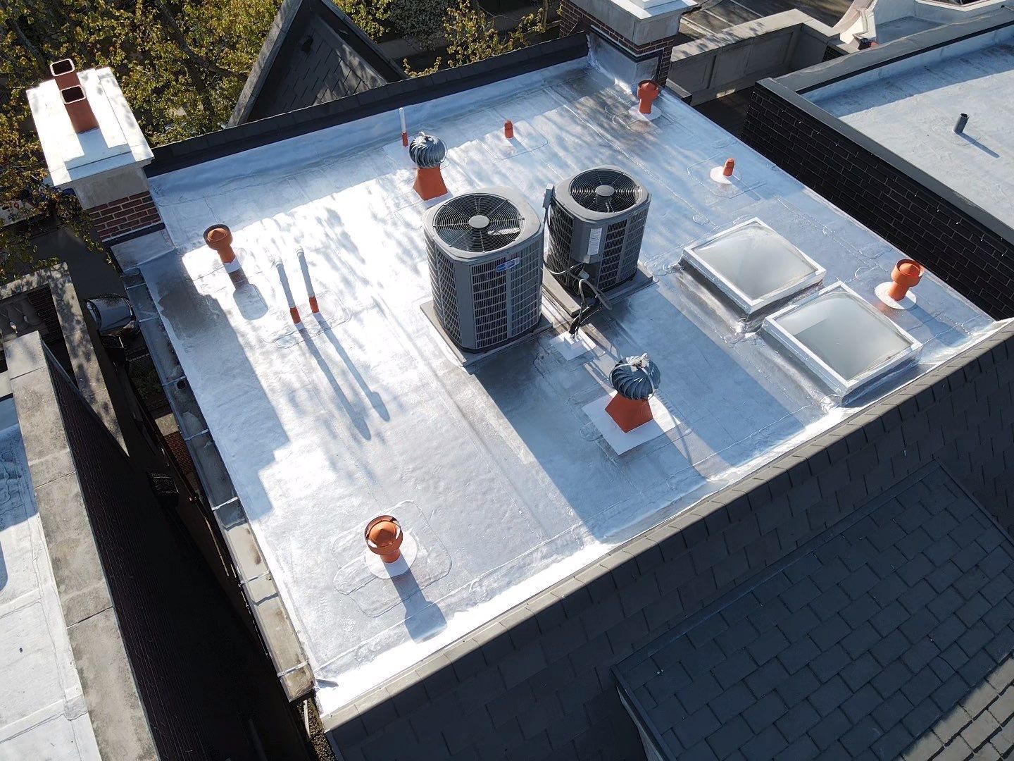 A roof with two air conditioners and two skylights on it