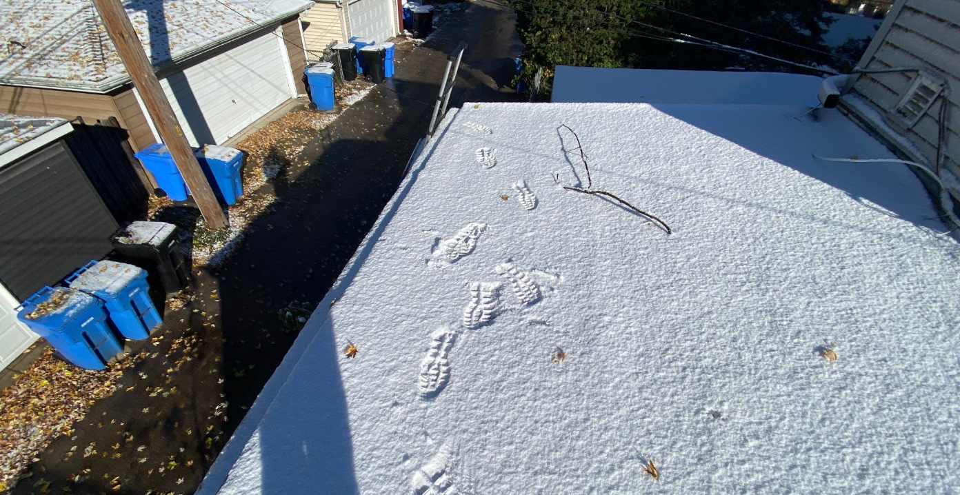 There are footprints in the snow on the roof of a house.
