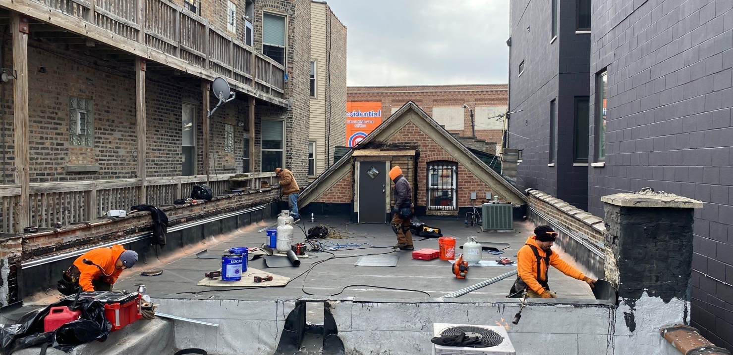 A group of men are working on the roof of a building.