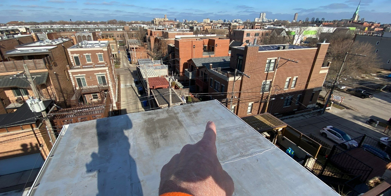A person is standing on top of a roof giving a thumbs up.