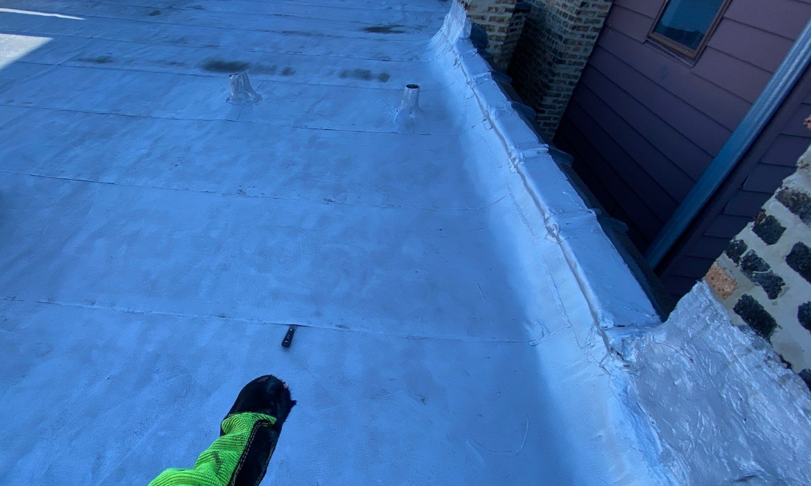 A person wearing green gloves is standing on a blue roof.