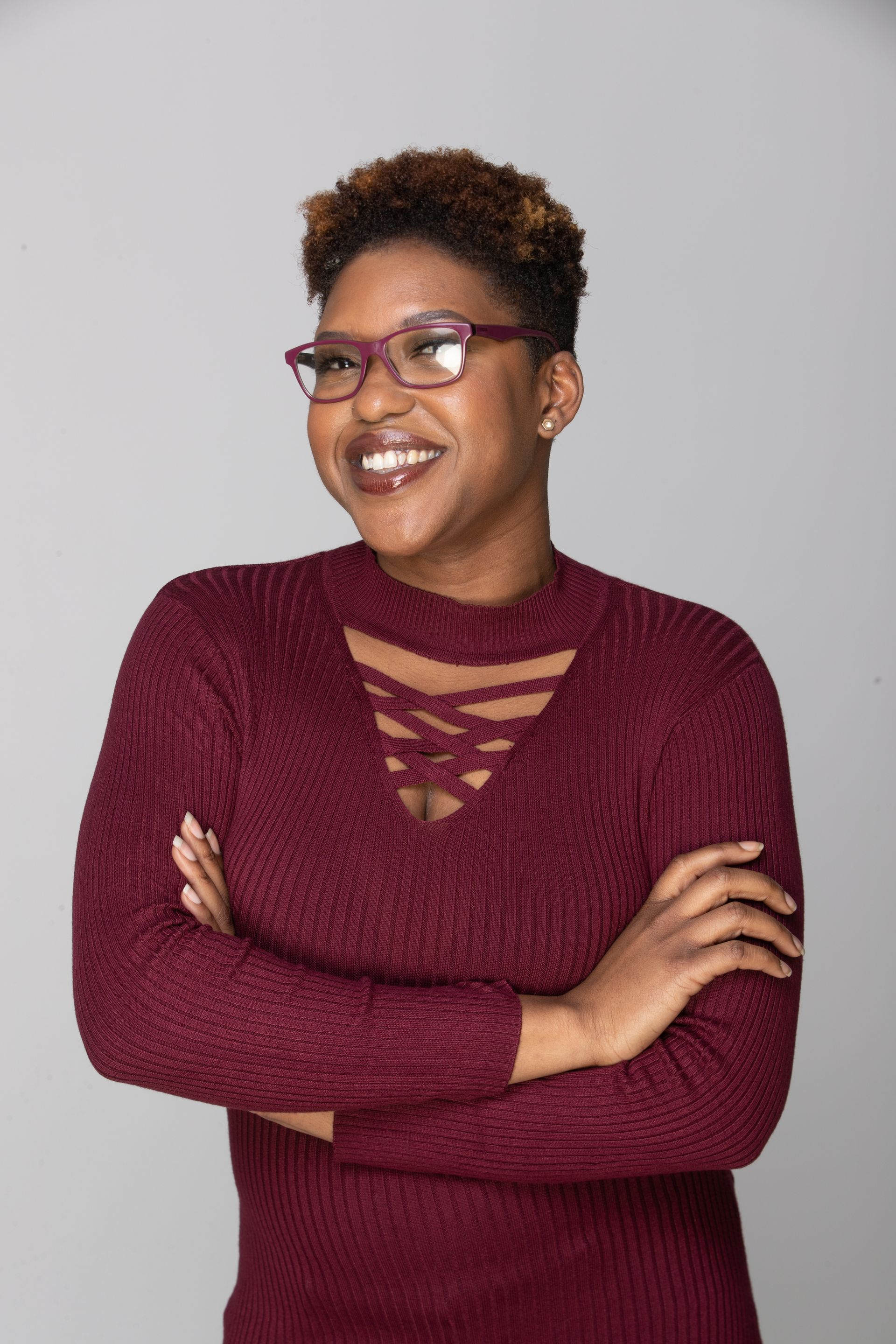 A woman is sitting at a desk with a laptop and a vase of flowers.