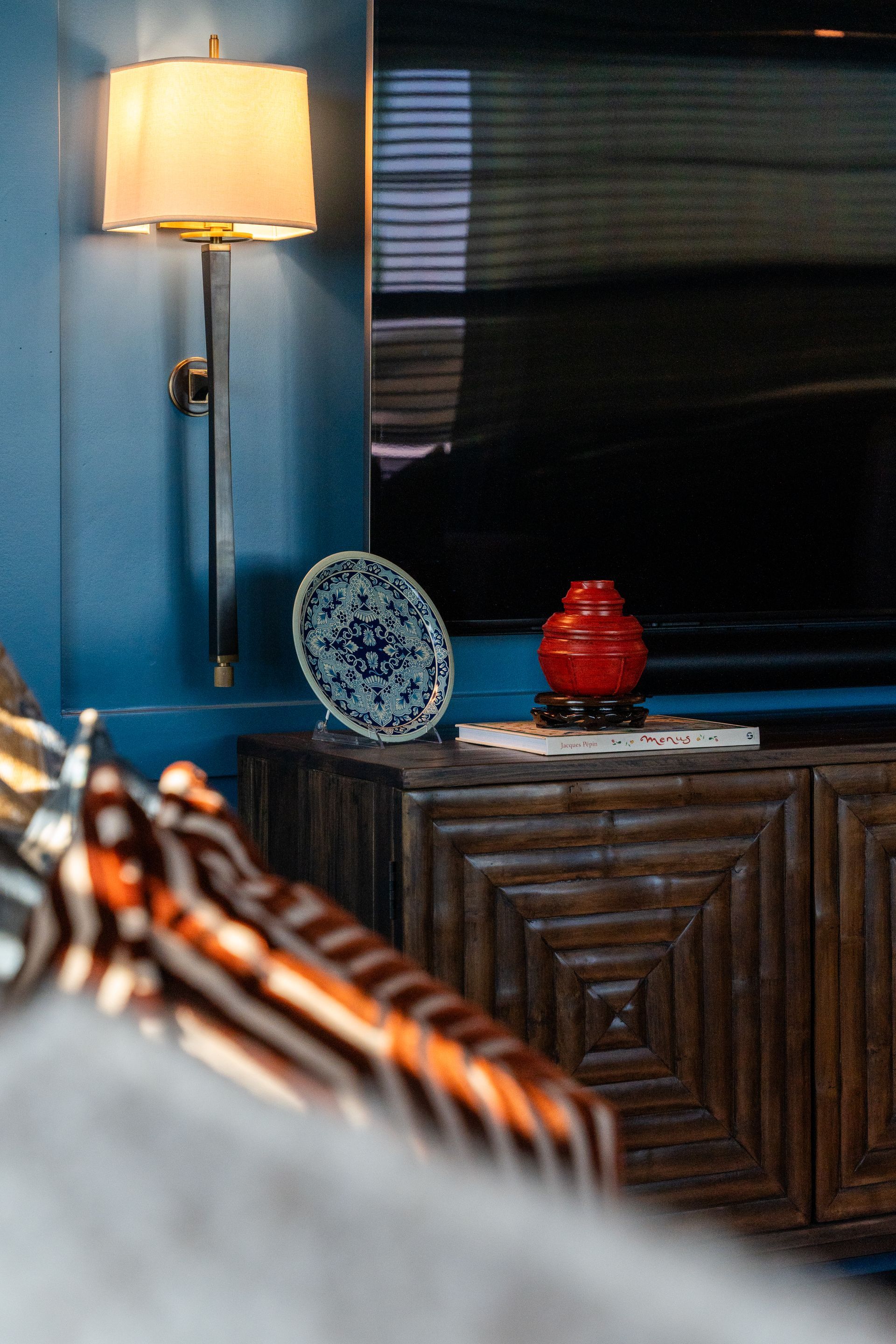 A living room with a lamp and a television on the wall.