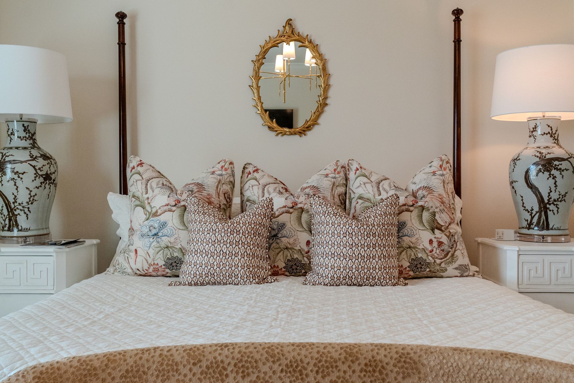 A bedroom with a bed , lamps and a mirror on the wall.