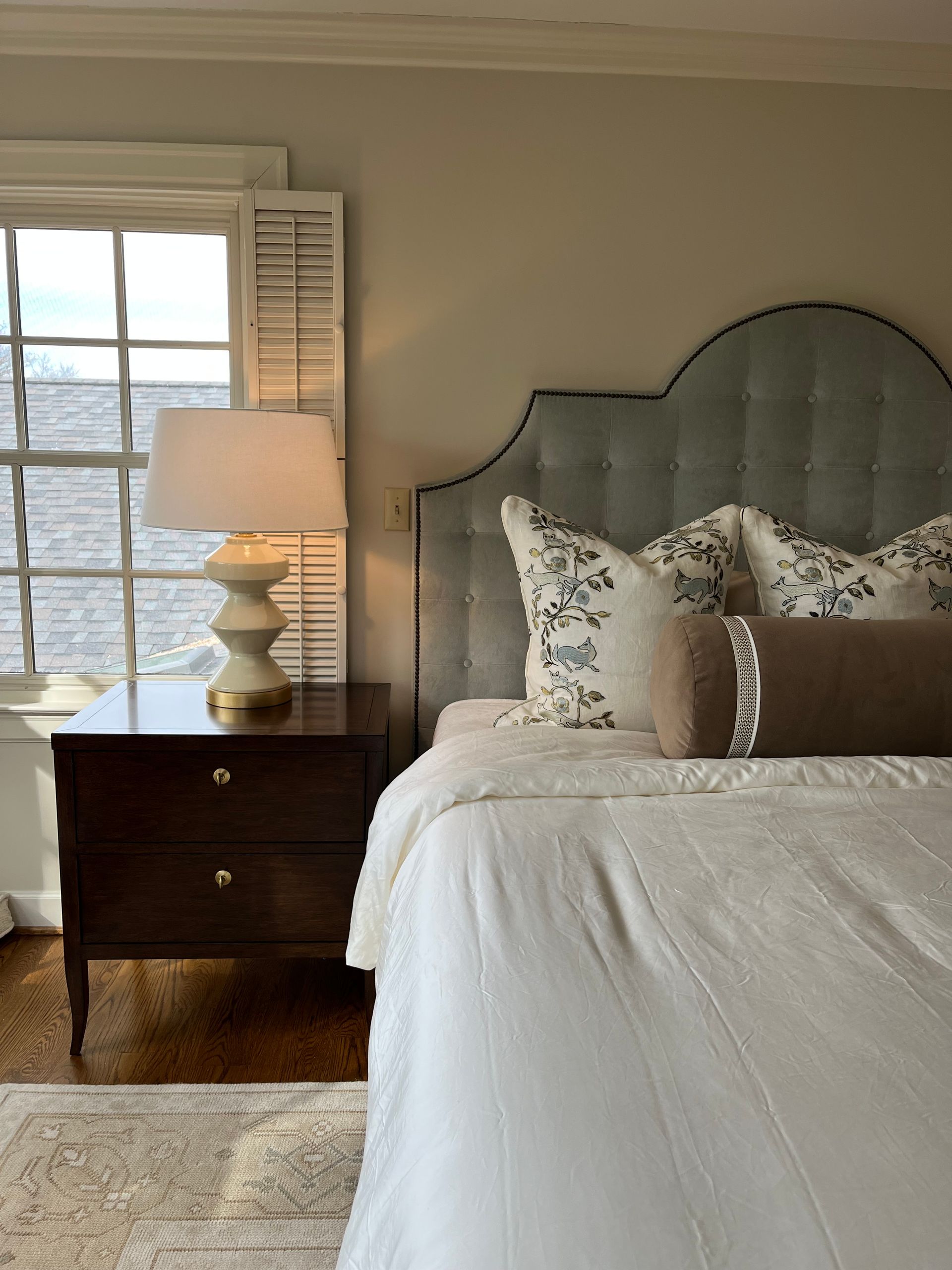 A bedroom with a bed , nightstand , lamp and window