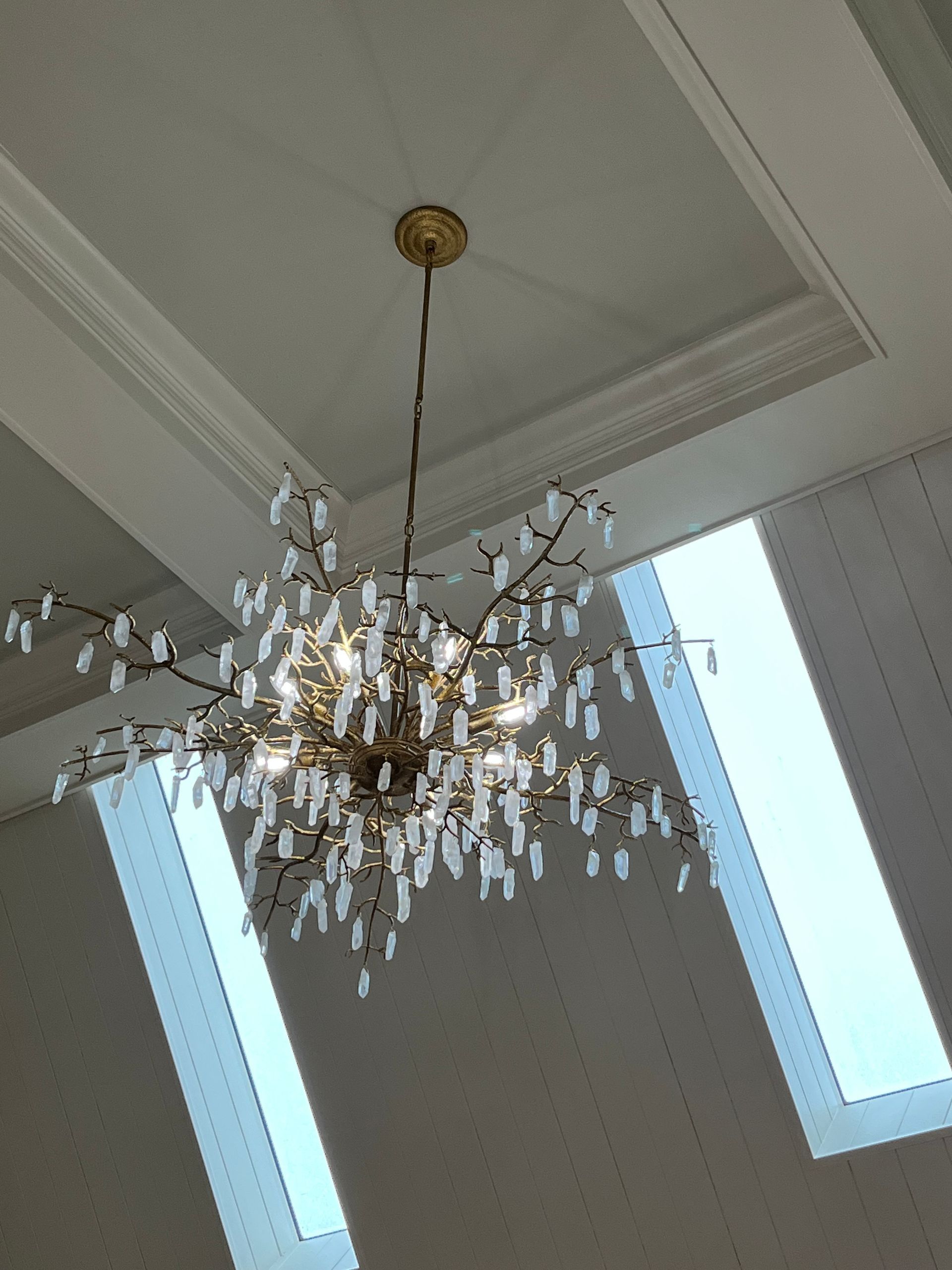A chandelier is hanging from the ceiling in a room with two windows