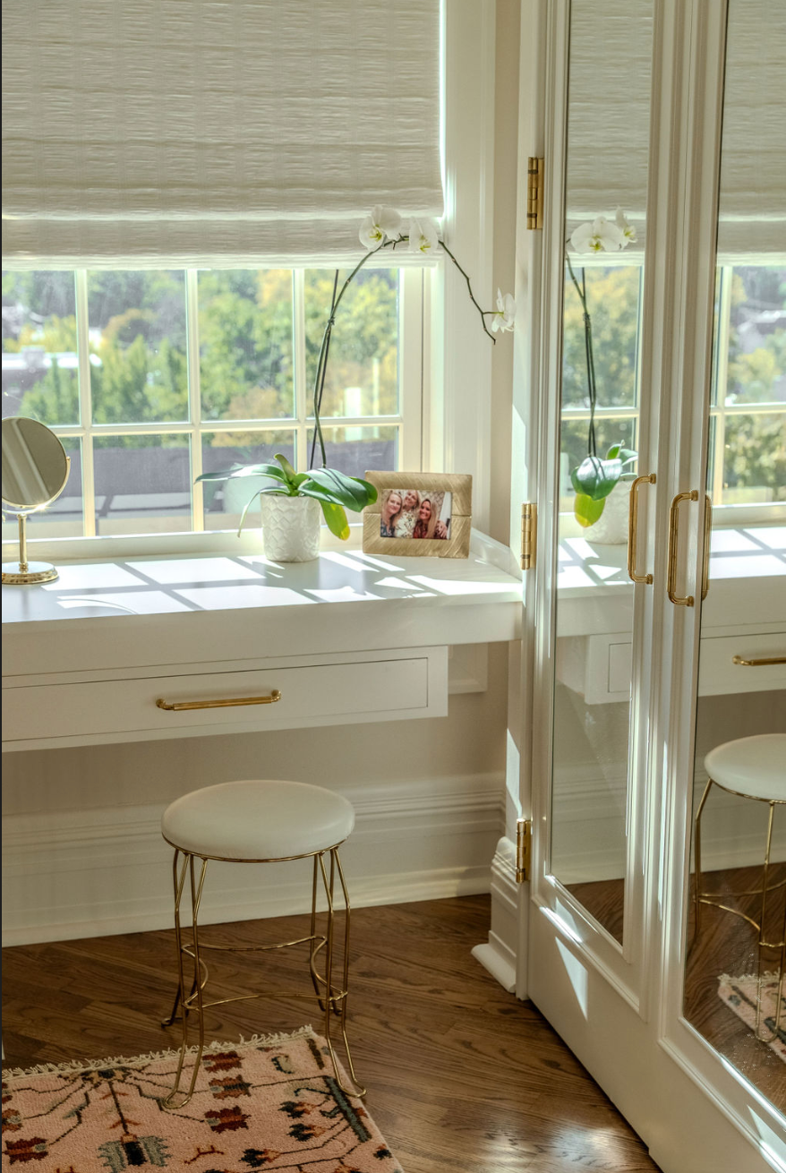 A room with a mirror and a stool in front of a window