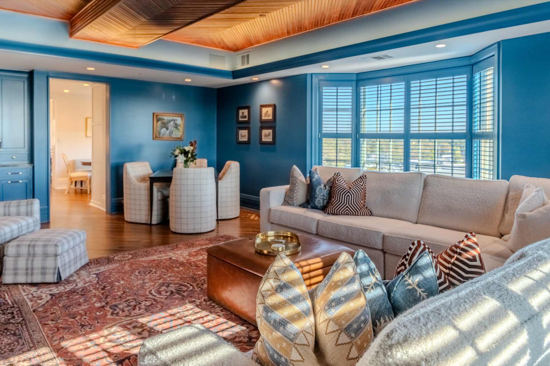 A living room with blue walls , a couch , chairs , and a table.