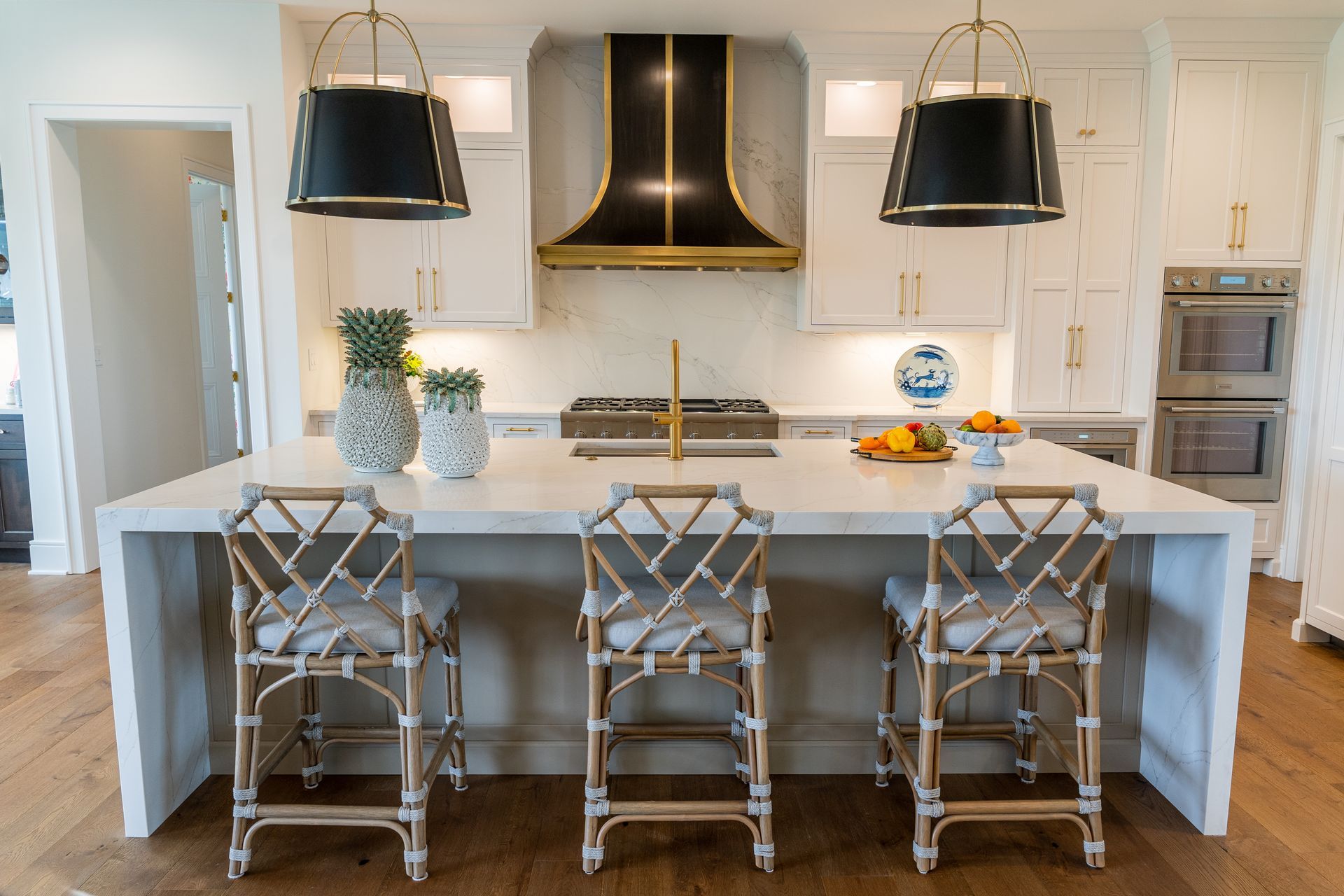 A kitchen with a large island , stools and a stove.