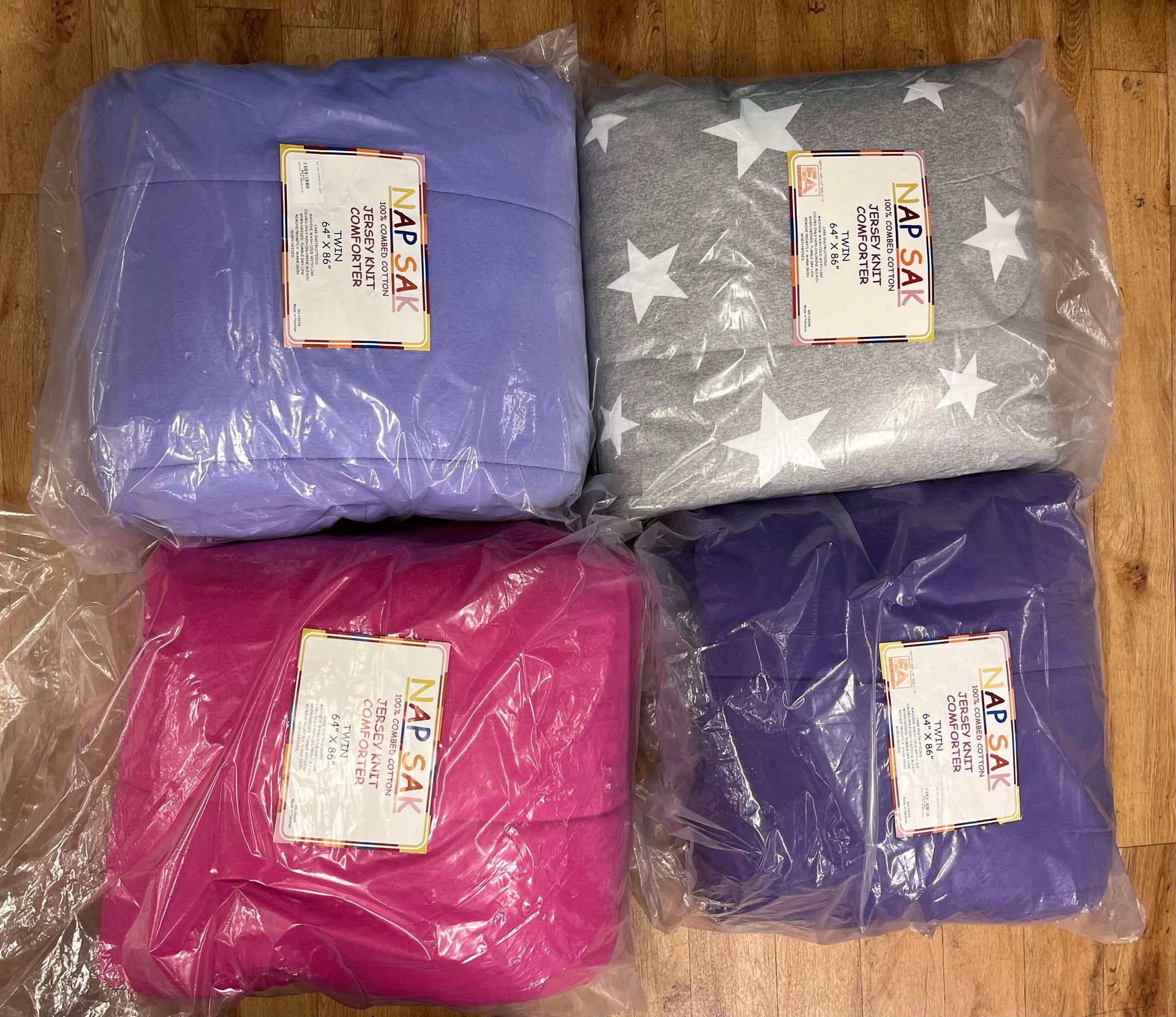 four bags of blankets are stacked on top of each other on a wooden table .