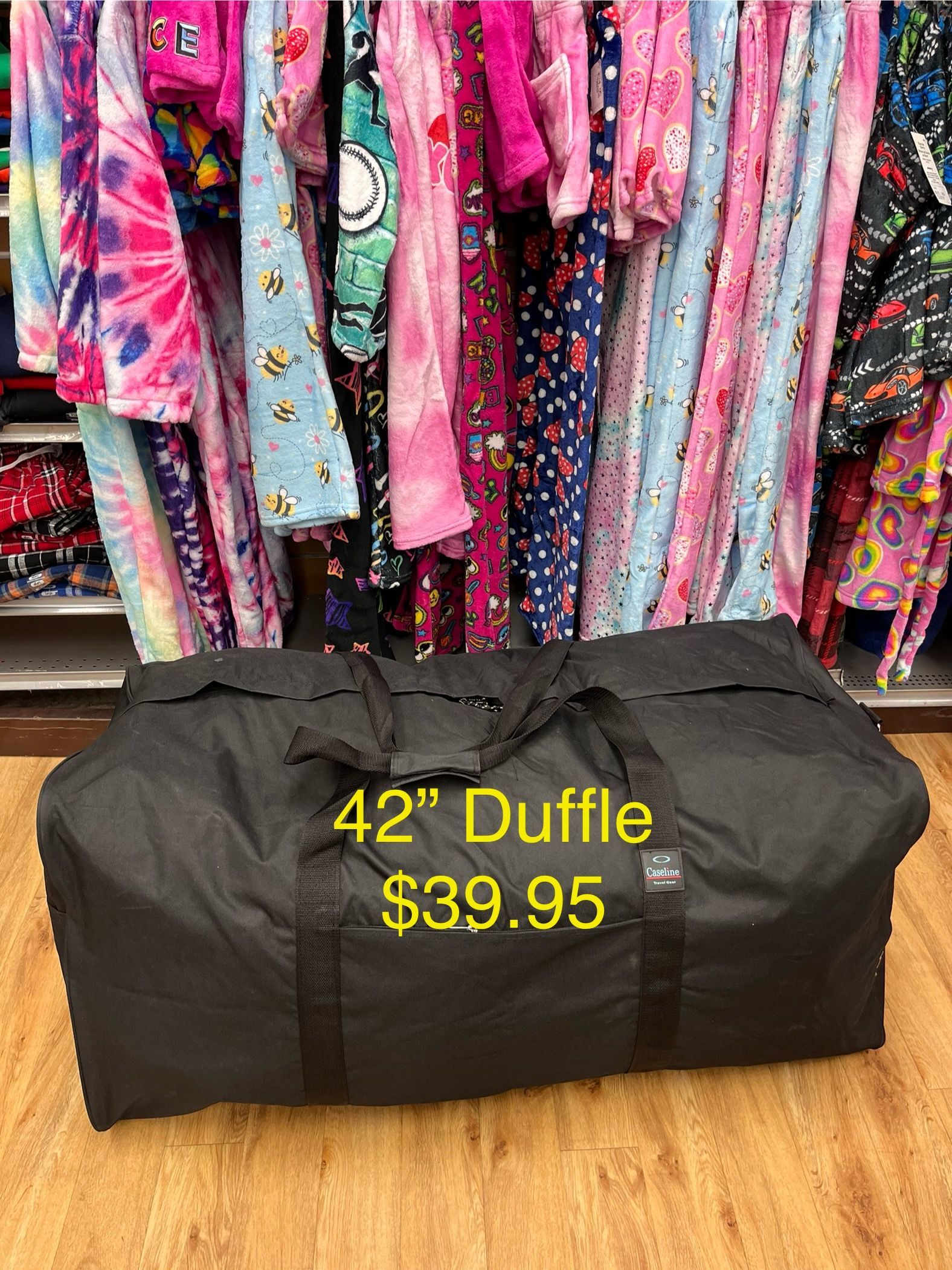 a large black duffel bag is sitting on a wooden floor .