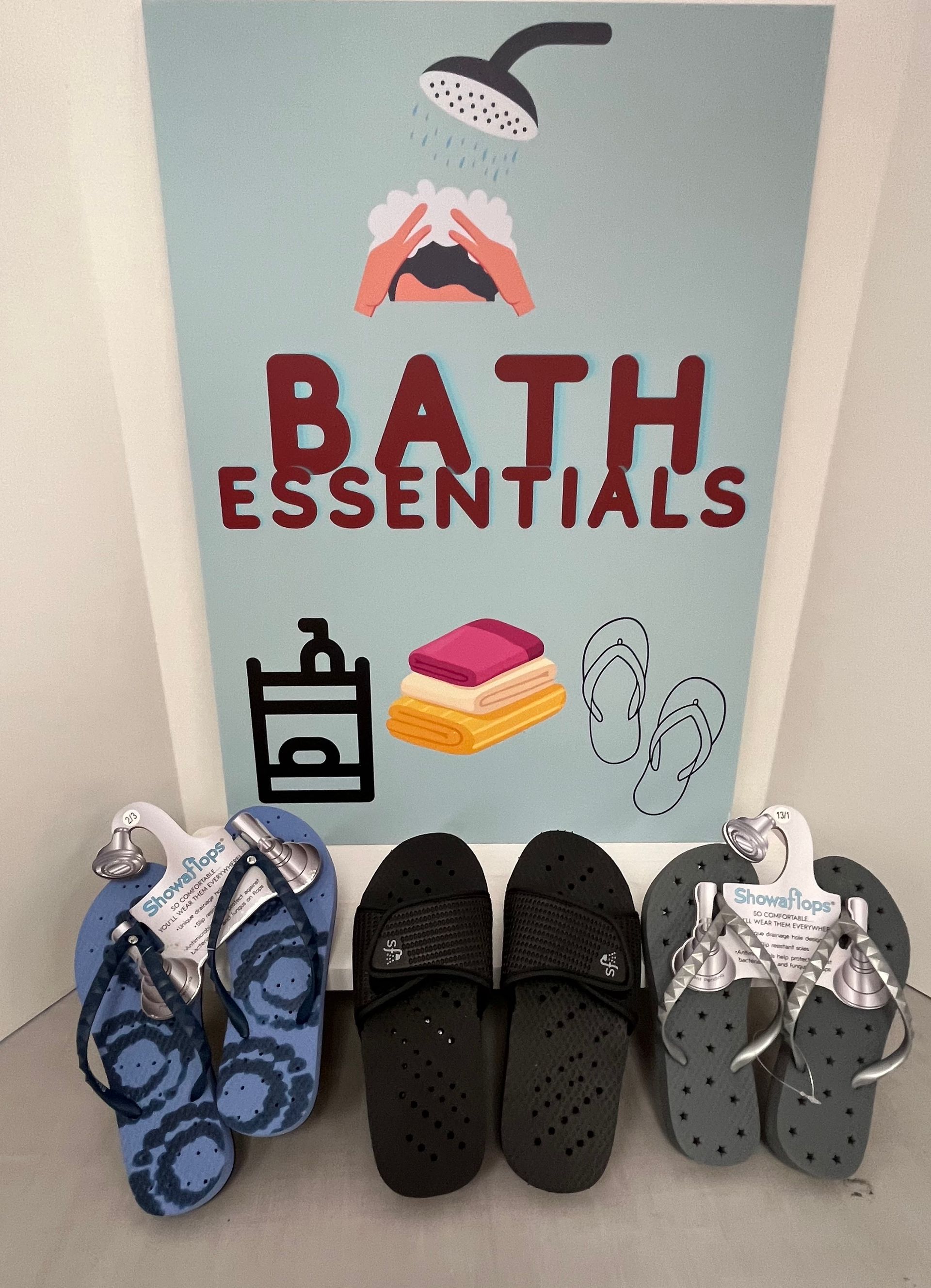 a sign that says bath essentials next to a pair of flip flops