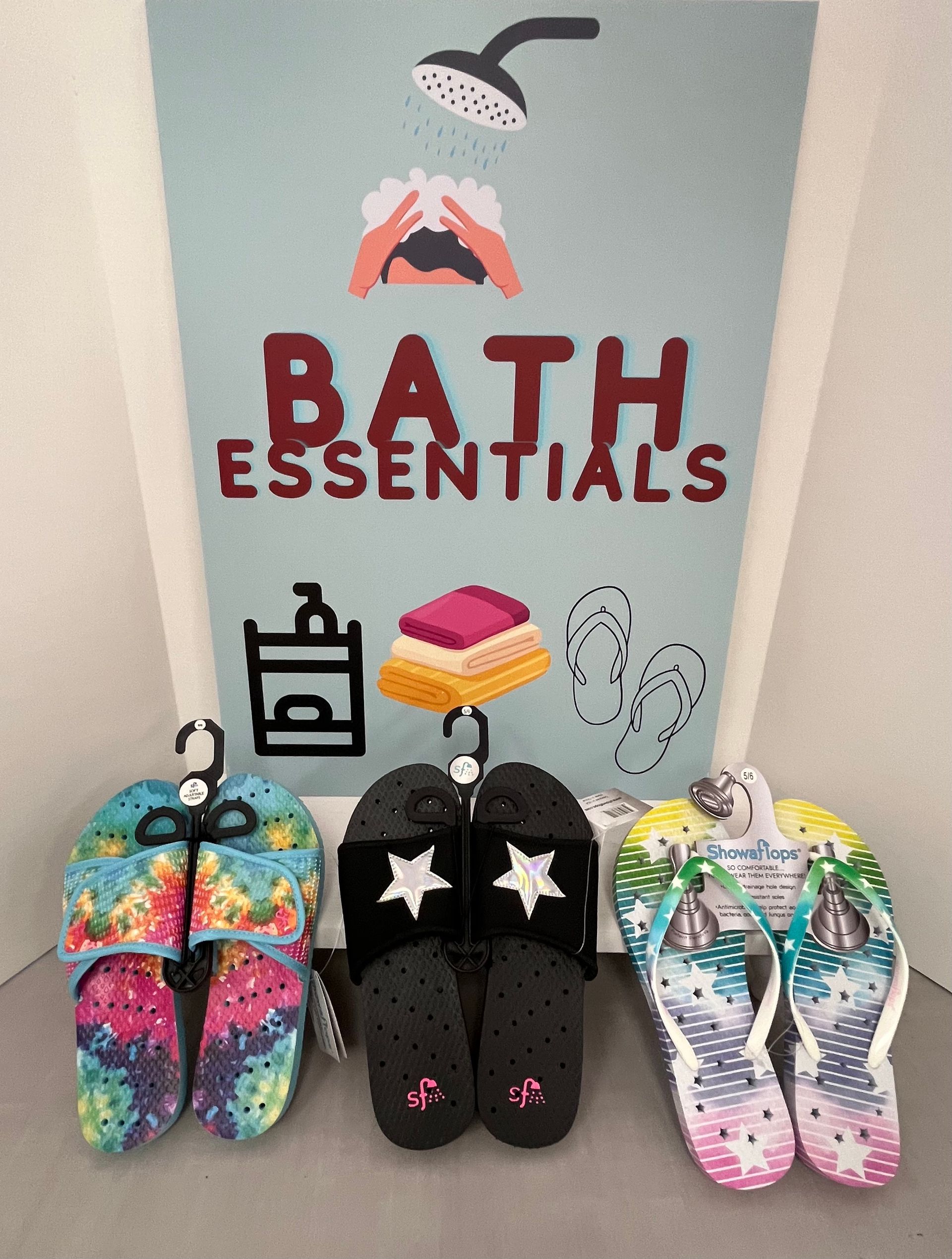 three pairs of slippers are sitting in front of a bath essentials sign
