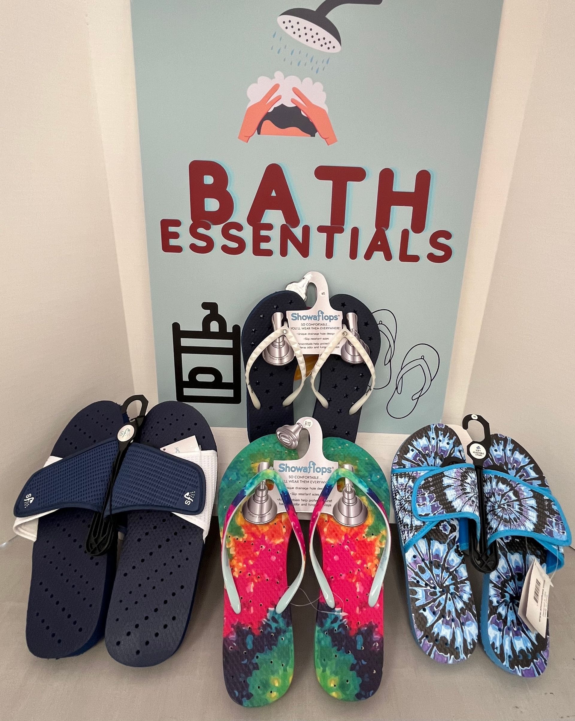 three pairs of flip flops are sitting in front of a bath essentials sign