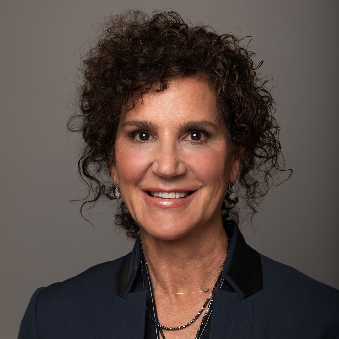 a woman with curly hair is wearing a blue jacket and a black collar .