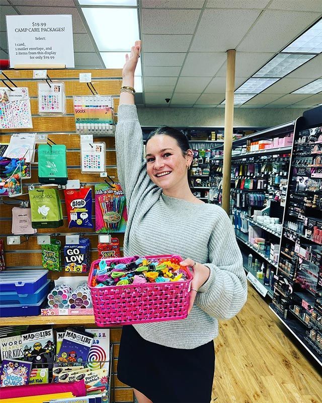 a woman is holding a pink basket in a store .