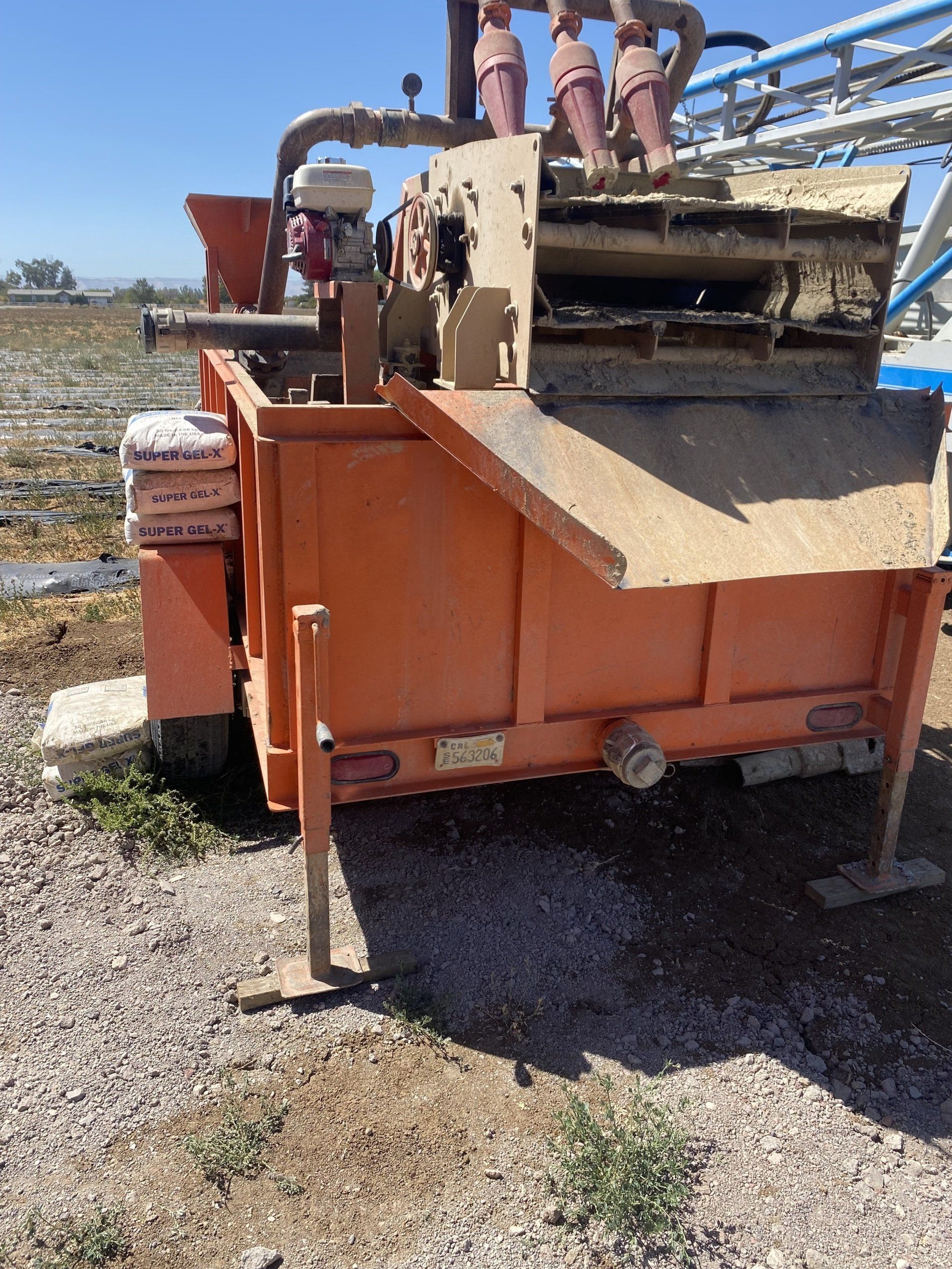 A large orange trailer is parked on a gravel road