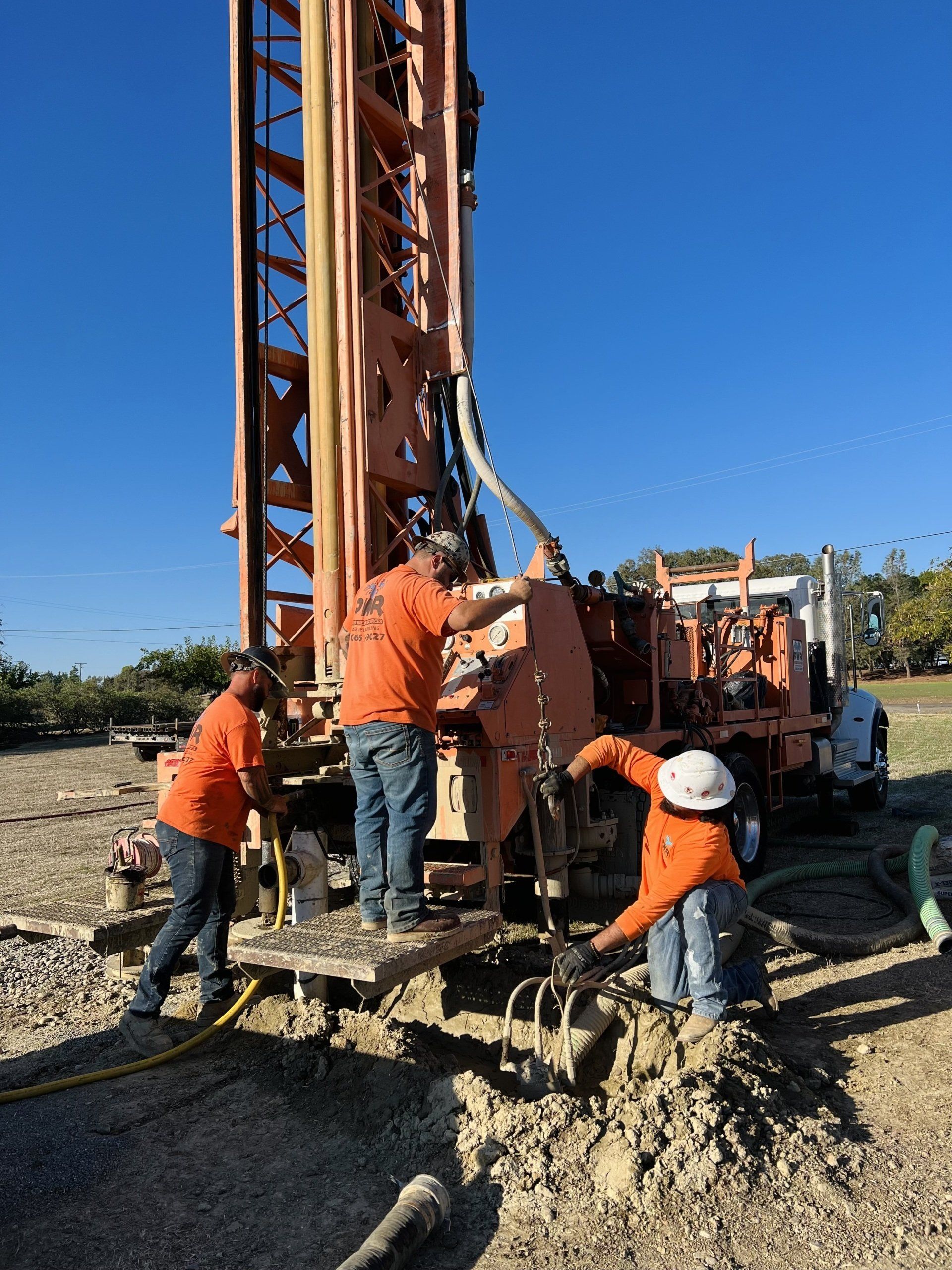A group of men are working on a machine in a field.