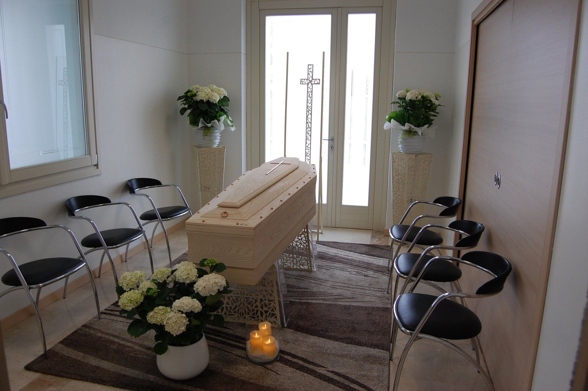 stanza dedicata alla veglia con bara, fiori e sedie intorno.