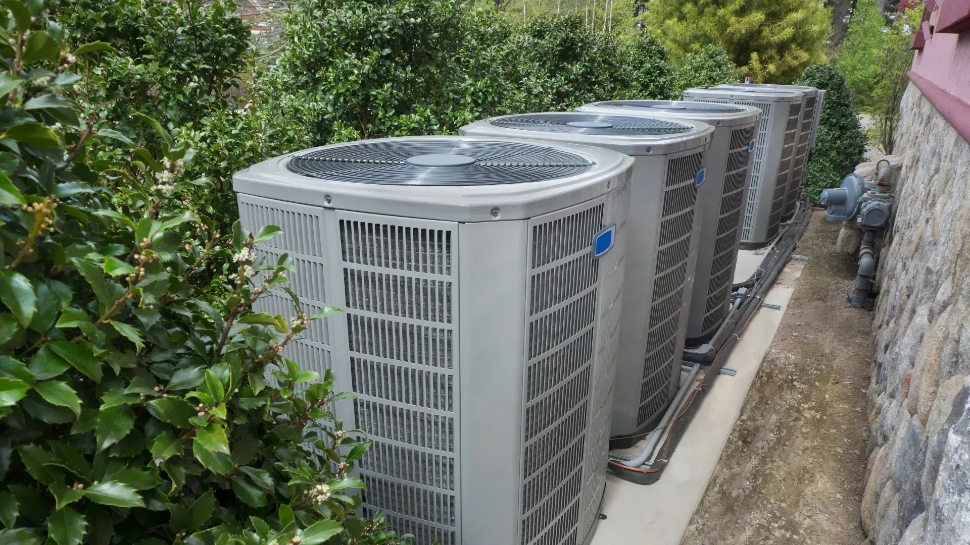A row of air conditioners are sitting next to each other on the side of a building.