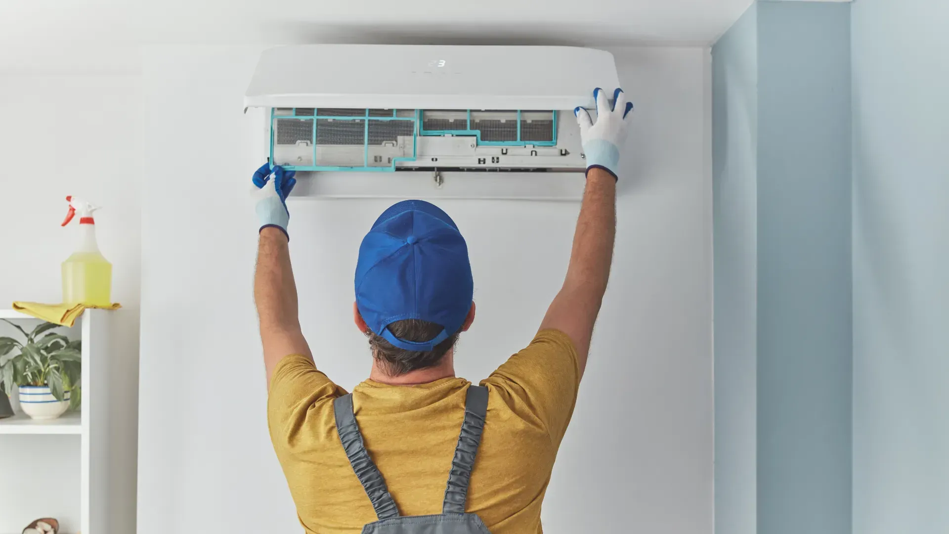A man is cleaning an air conditioner in a room.