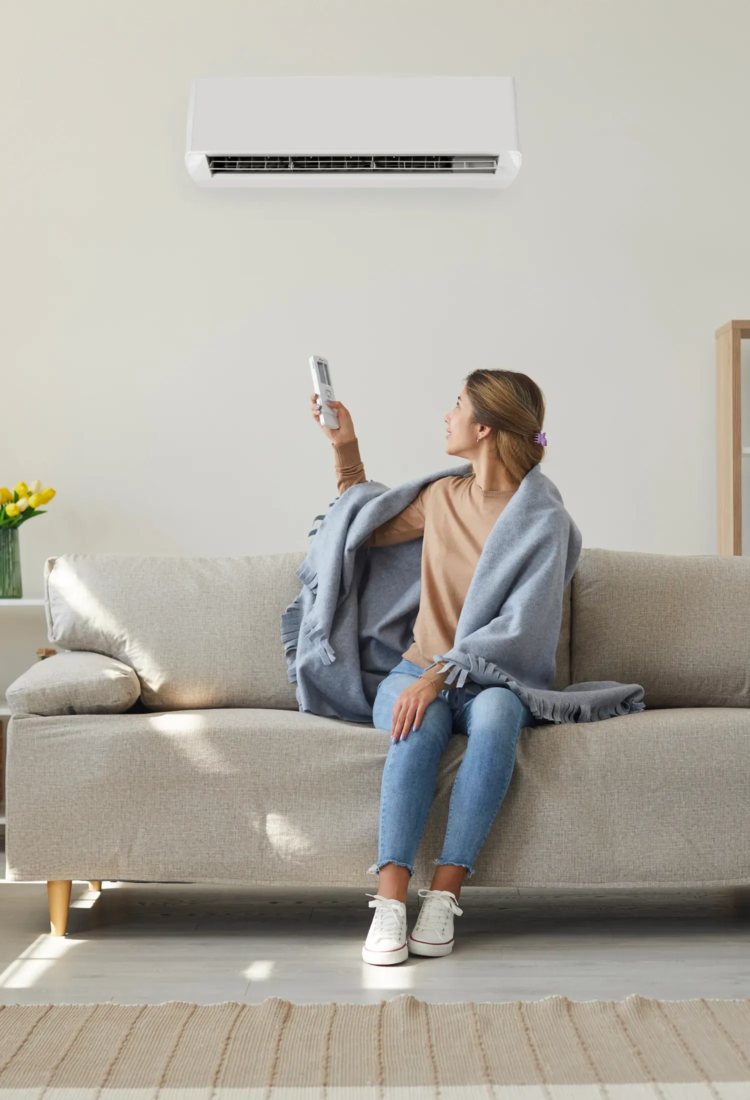 A woman is sitting on a couch holding a remote control.