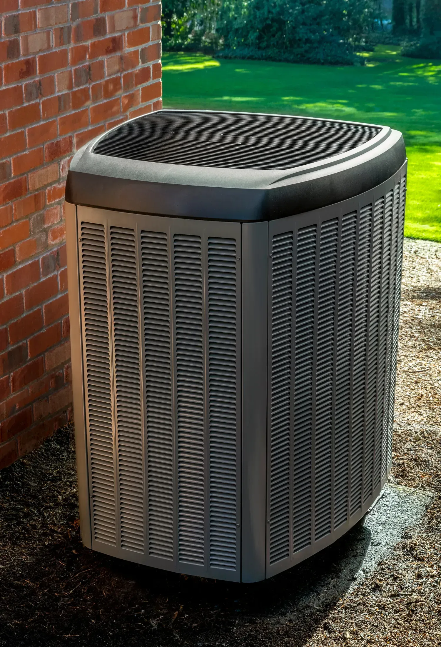 A large air conditioner is sitting on the side of a brick building.