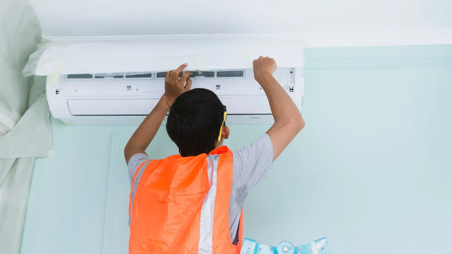 A man is installing an air conditioner in a room.