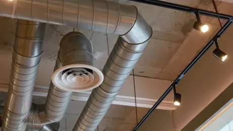 A bunch of metal pipes are hanging from the ceiling of a building.