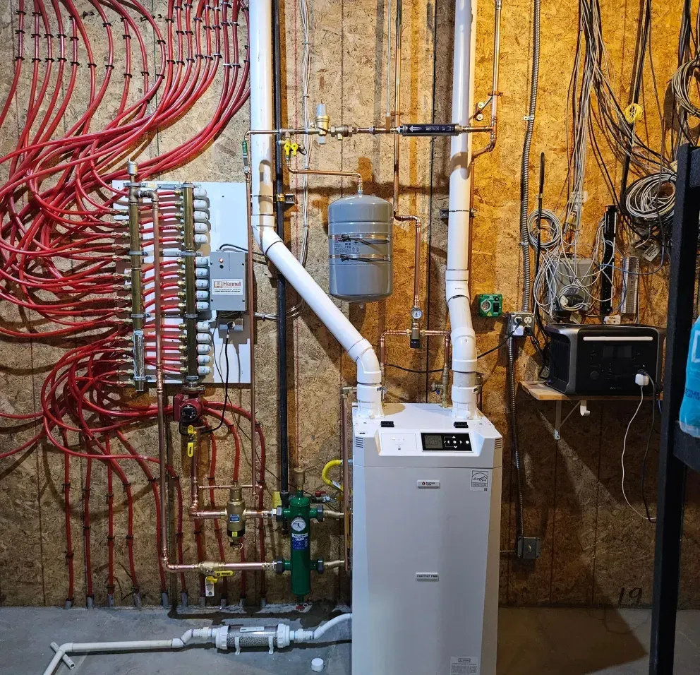 A blue water heater is sitting in a basement next to a boiler.