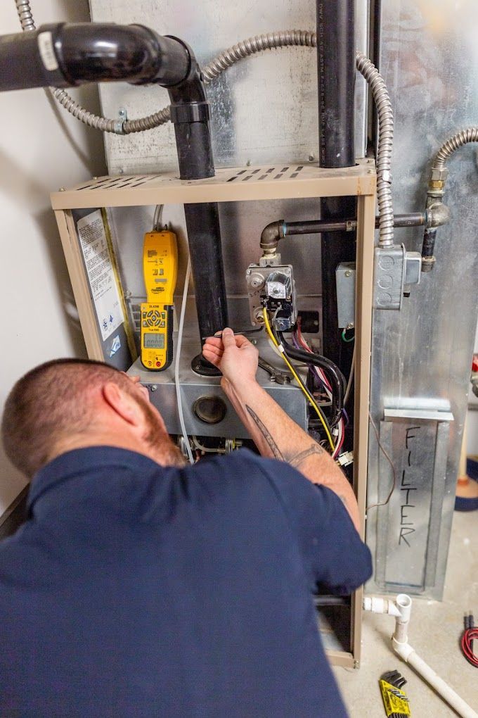 A man is working on an air conditioner in a basement.