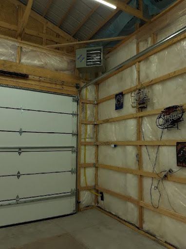 A garage with a garage door and a heater on the wall.