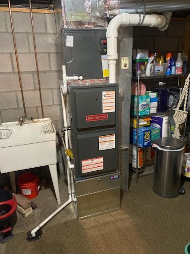 A furnace is sitting in a basement next to a sink.