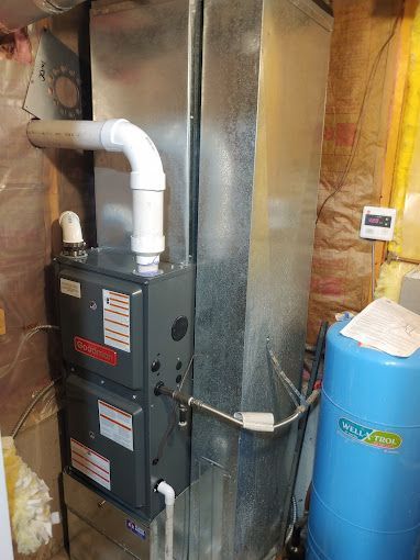 A gas heater is sitting next to a water tank in a basement.
