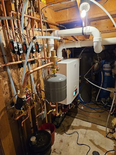 A boiler is being installed in a basement with copper pipes.