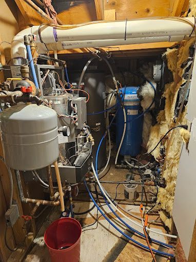 A room with a lot of pipes and a red bucket.