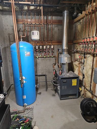 A blue water heater is sitting in a basement next to a boiler.