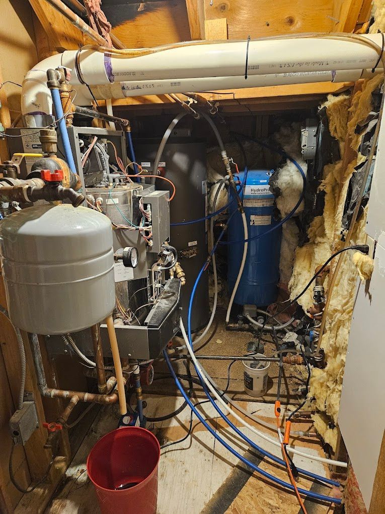 A bunch of pipes are connected to a boiler in a room.