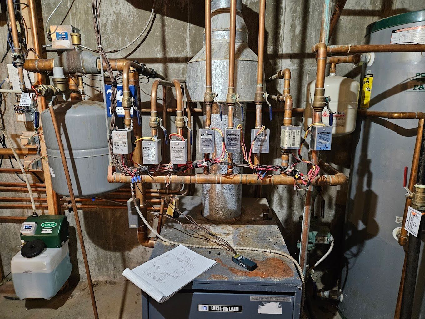 A man is working on an air conditioner in a basement.