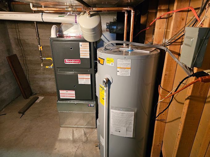 A water heater is sitting next to a furnace in a basement.