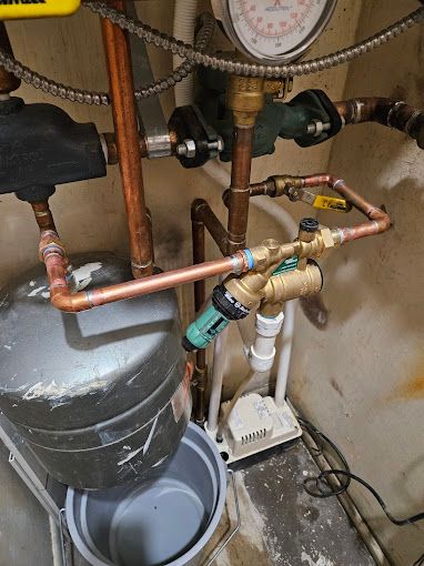 A close up of a water heater with copper pipes and a pressure gauge.