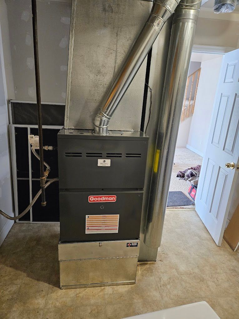 A furnace is sitting in a basement next to a water tank.