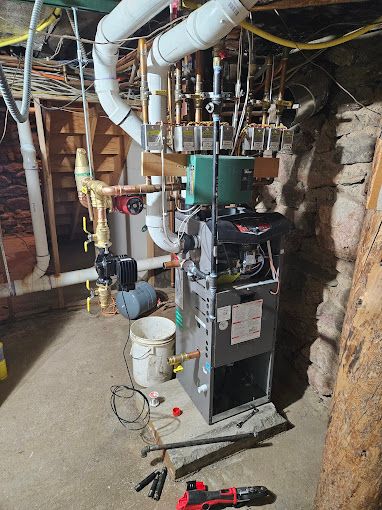 A boiler is being repaired in a basement.