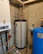 A water heater is sitting in a room next to a boiler.
